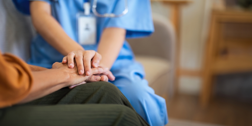 Healthcare professional holding patient's hand compassionately