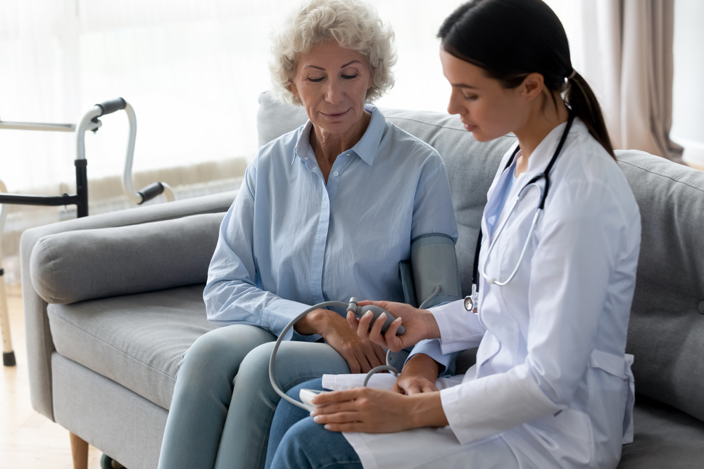 Healthcare professional checking blood pressure of elderly patient