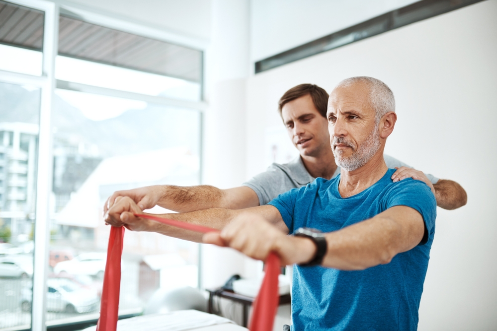Physical therapist assisting elderly patient with exercise