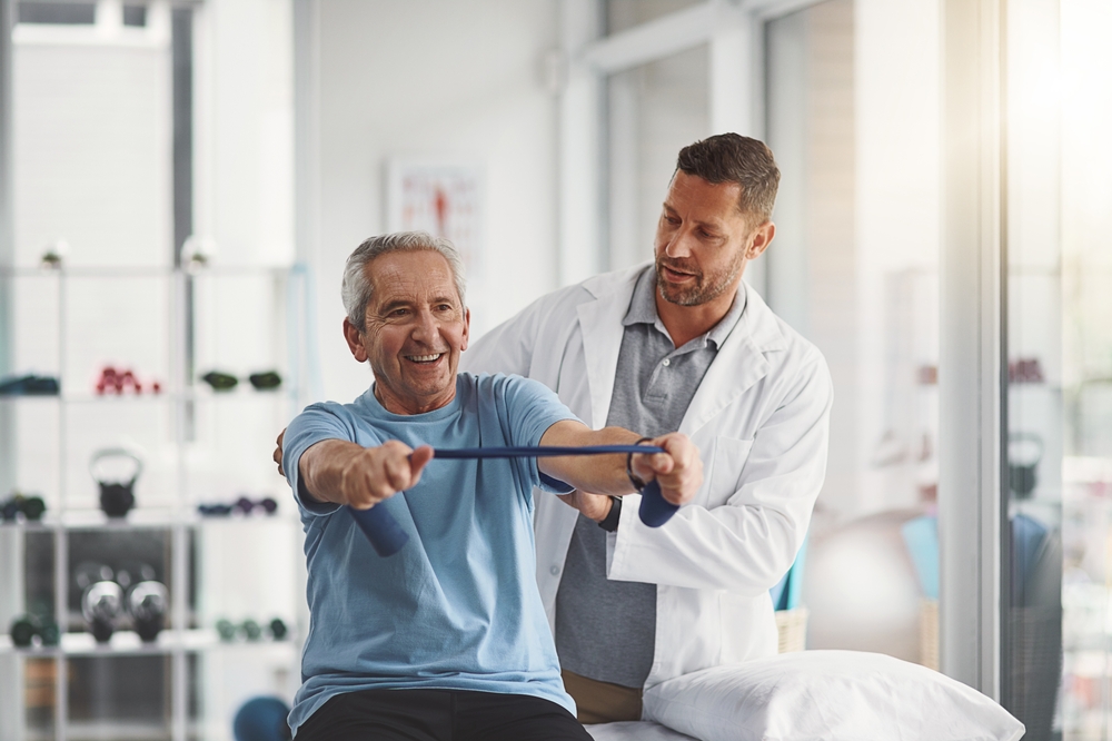 Physical therapist helping elderly patient with exercise band