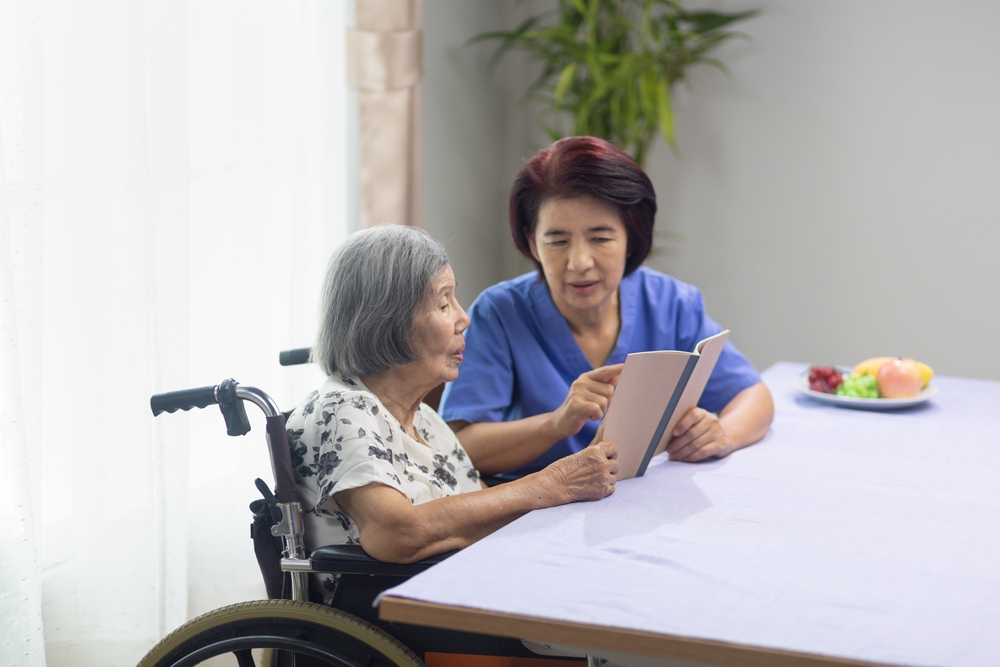 Speech therapist working with elderly resident on tablet communication