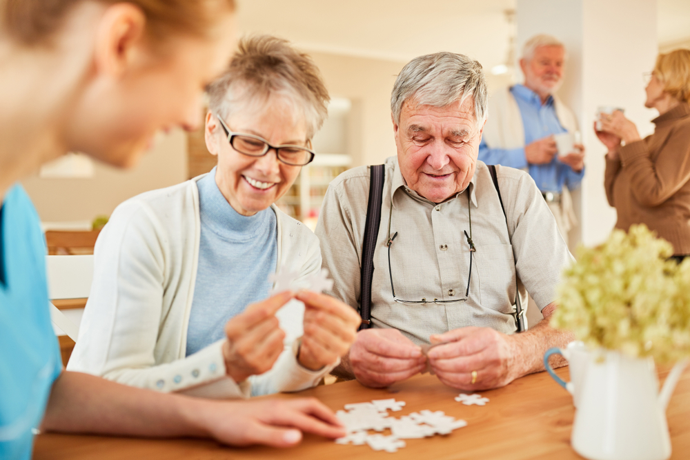 Social worker assisting senior residents with a puzzle activity